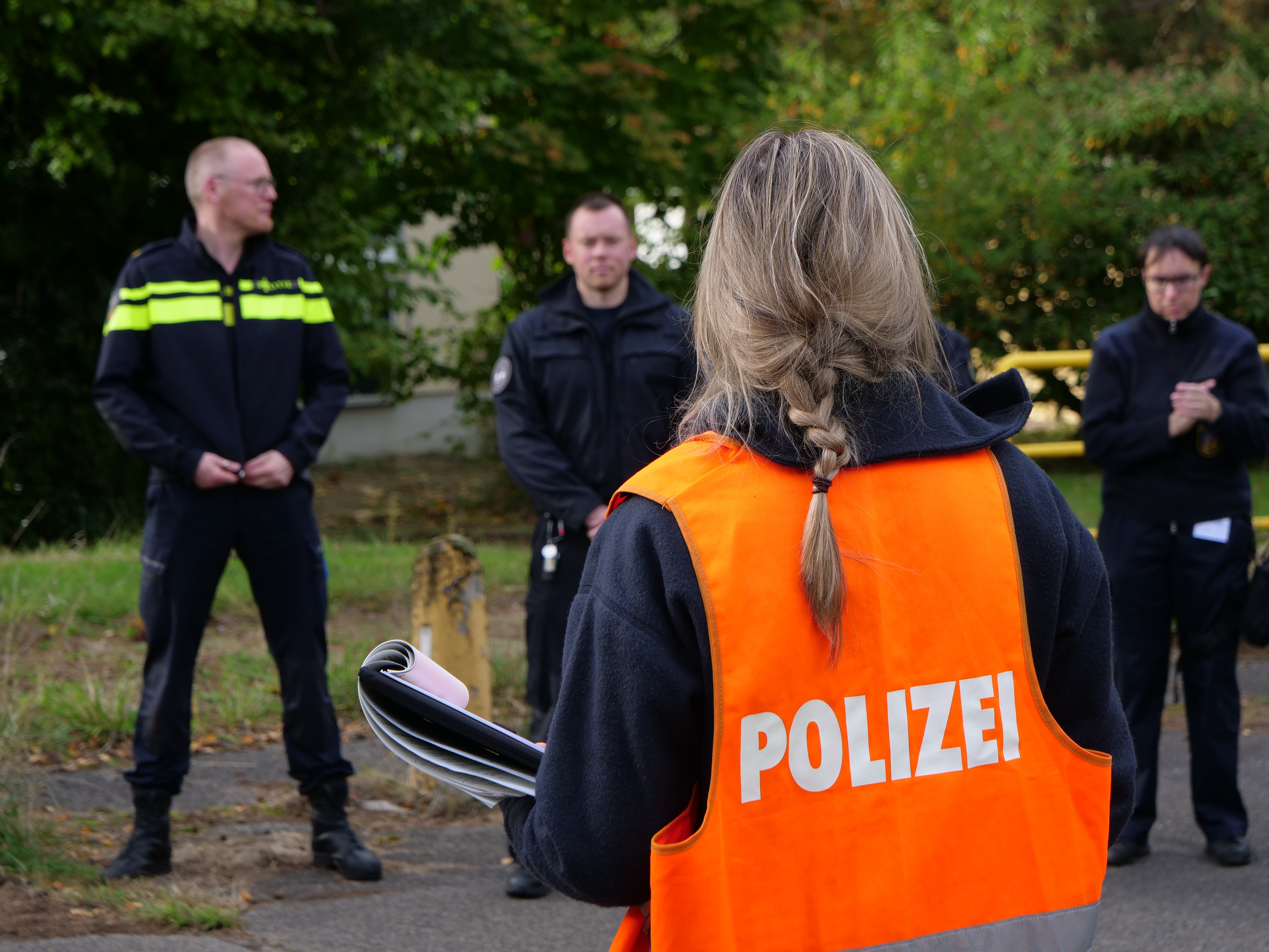 Eine deutsche Polizistin und zwei niederländische Polizisten stehen sich gegenüber.