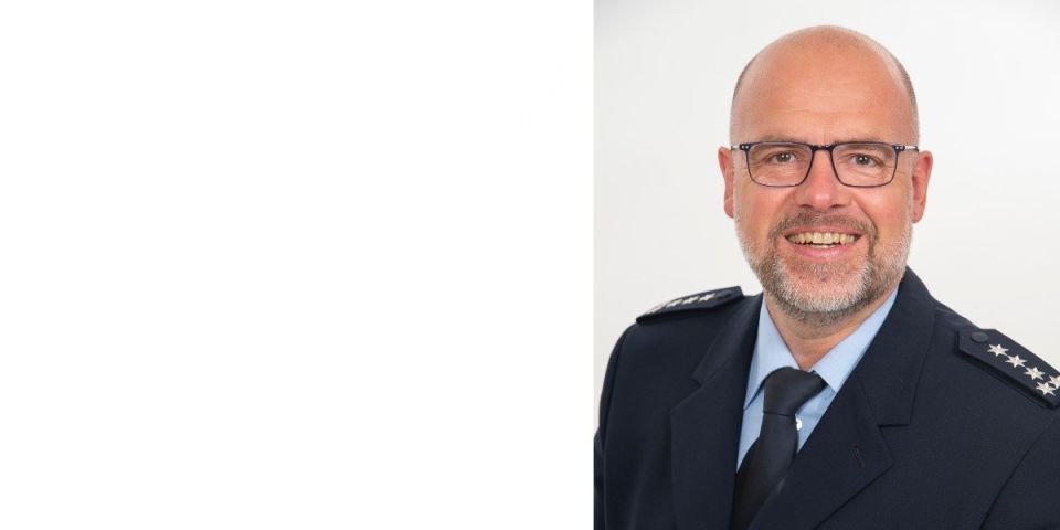 50-jähriger Mann in Uniform, mit Brille und Drei-Tage-Bart lächelt in die Kamera.